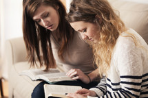 Friends reading Bibles together on a couch. 
