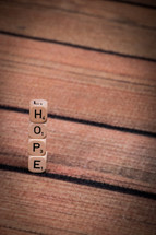 A stack of dice, spelling "hope," on a wooden table.