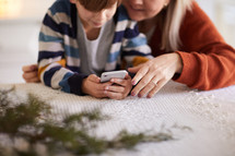 close up of mom helping young son use a smartphone. 