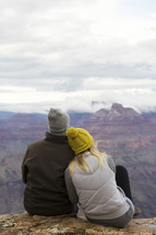 couple sitting on a mountaintop snuggling 