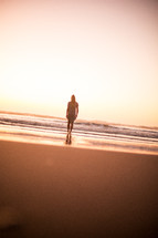 woman walking on a beach at sunset 