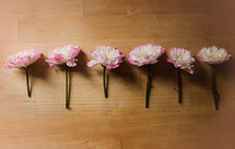A row of pink flowers on a wooden table.
