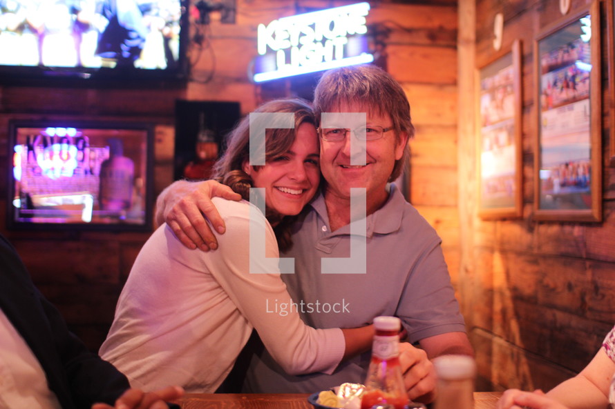a woman hugging her father in a bar