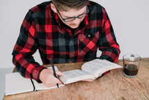 a man reading a Bible and writing in a journal 