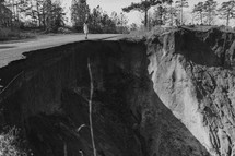 a woman standing at the edge of a collapsed road