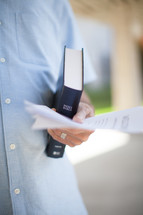 man holding a Bible and church bulletin 