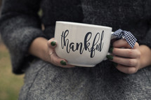 a woman holding a Thankful mug 