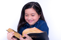 Smiling girl reading the Bible.