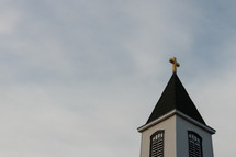 Church steeple with golden cross with sky in background