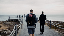 men walking on a  boardwalk heading towards a beach 