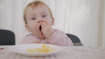 Cute baby eating an orange next to a table