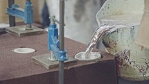 Workers in a foundry pouring liquid Aluminum to a sand cast