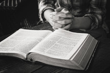 a teen girl praying near an open Bible 