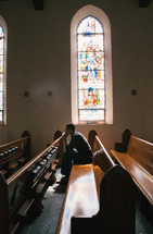 a man sitting in an empty church praying 