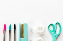 pens, stapler, tape, and scissors on a white background 