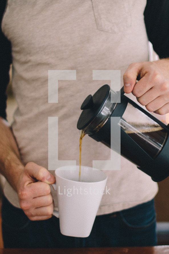 a man pouring coffee into a mug