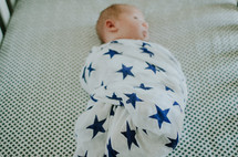 a swaddled baby in a crib 