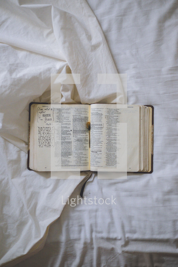 notes in an open Bible on a bed 