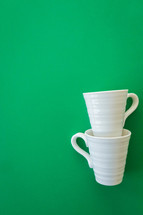 stacked white mugs on a green background 