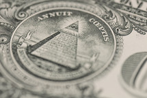 Closeup of the back of a dollar bill showing the Pyramid, eye emblem