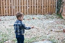 a boy child standing under falling leaves 