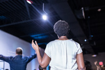 a woman standing in praise at a conference 