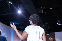 a woman standing in praise at a conference 
