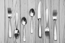 fork, knives, spoons on a wood floor 