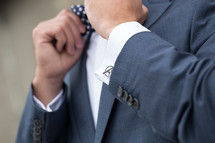 a groom with Avenger cuff links adjusting his bow tie 