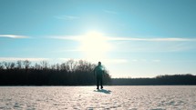 Silhouette of a man walking into the distance through the snow during sunset. A loner walks across a large meadow of snow. Failure and loneliness.