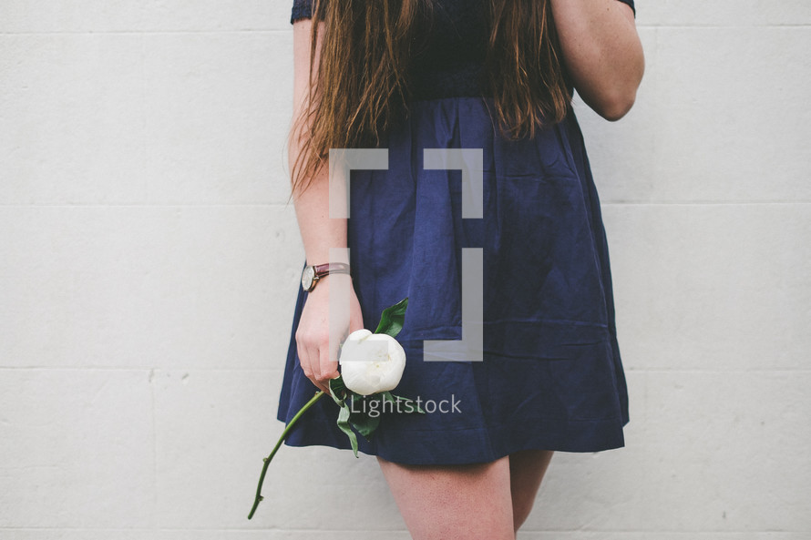 a young woman holding a white flower in her hand