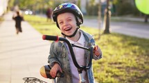 Happy smiling boy in helmet riding a cycling. Little boy learns to ride a bike in the park near the home. Sport activity for children. Child development concept.