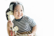 a toddler girl on an antique phone 