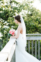 a bride standing outdoors with a bouquet of flowers 