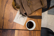 coffee cup and backpack on a wood table 