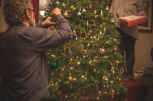 a man decorating a Christmas tree 