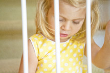 toddler girl looking through bars