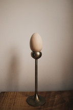 wooden egg on candlesticks against a wood background with copy space 