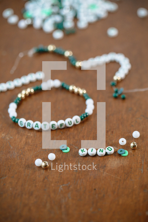 Jar of green, white, and gold beads with word - grateful and kind