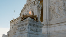 the flame of glory burning under a statue in Rome