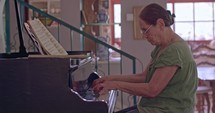 Senior woman playing a large grand piano at her home