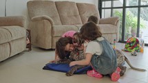 Three kids playing with a German pointer dog inside a house