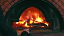 Italian pizza is cooked in a wood-fired oven. Pizza oven in restaurant. Tasty pizza getting from oven.