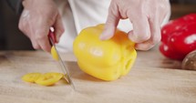 Slow motion close up of a chef knife slicing a yellow bell pepper