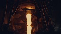 Slow motion of Molten glass pouring out of a Glass melting furnace in a bottle production facility.