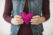 a woman holding a pink felt heart 