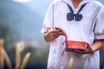 Girl standing and holding Bible at outdoors. Christian concept.