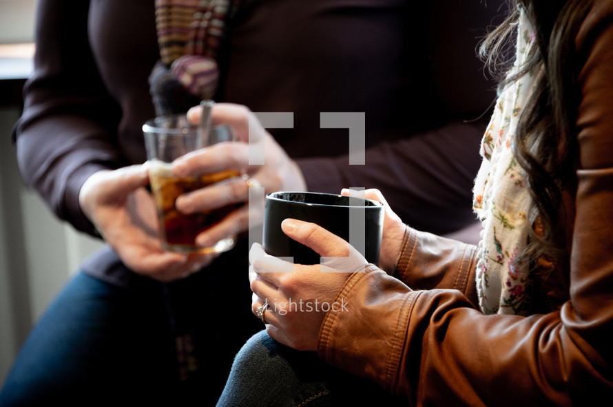 woman talking holding drinks in their laps 