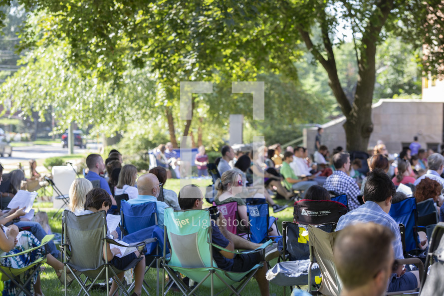 people sitting in chairs at an outdoor concert