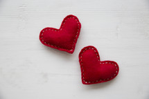 red felt hearts on a white wood table.